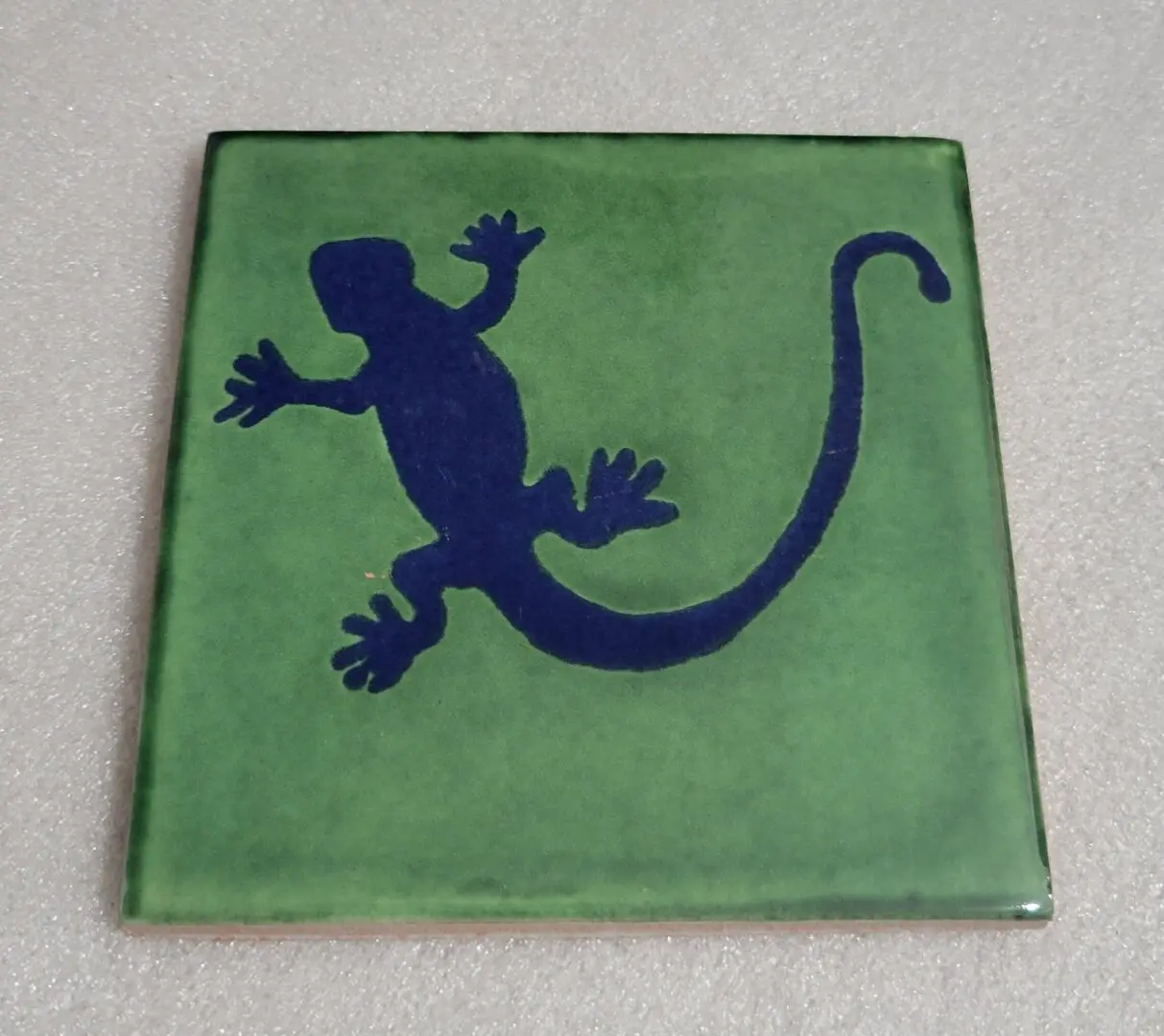Green tile with a blue gecko silhouette design.