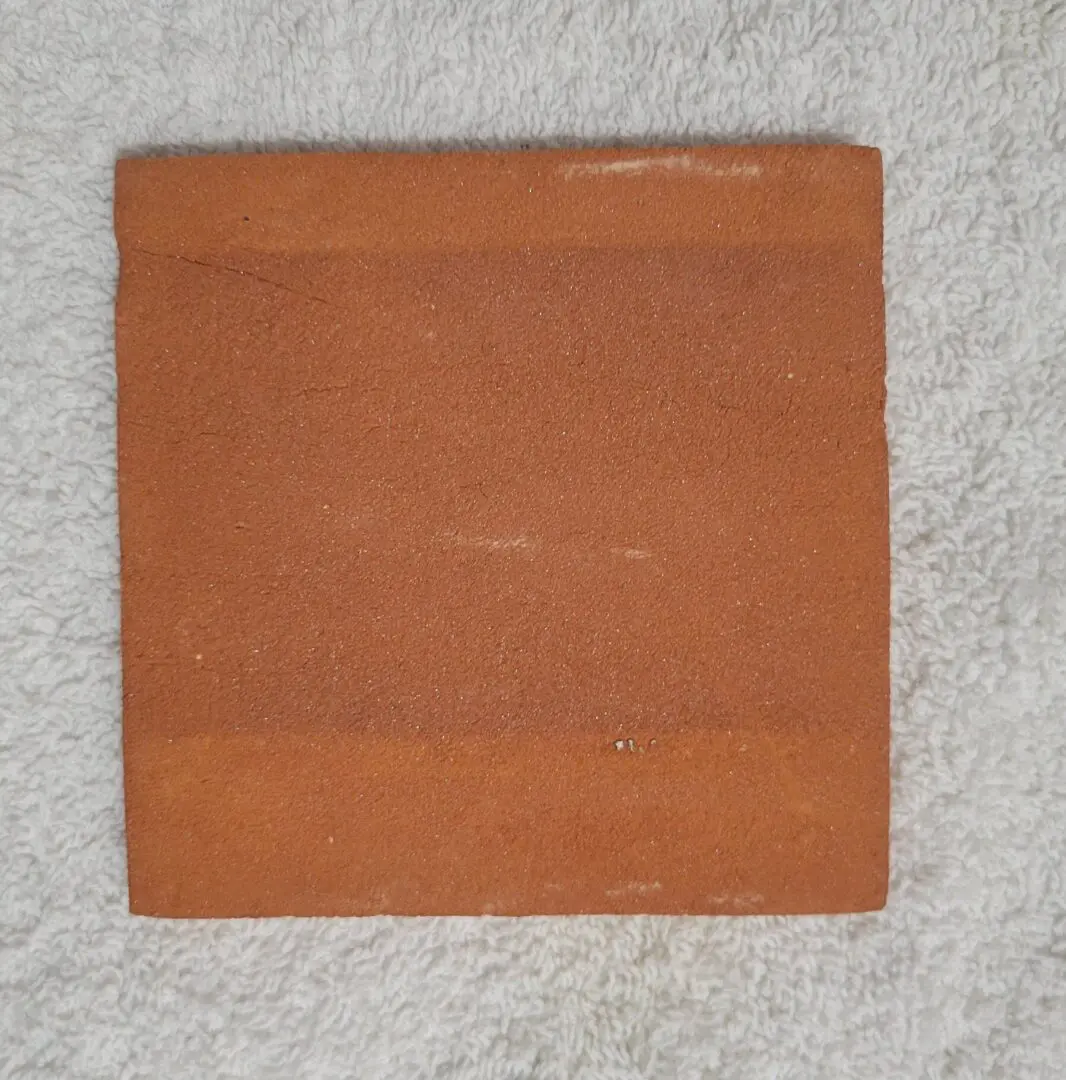 Square terracotta tile on white towel