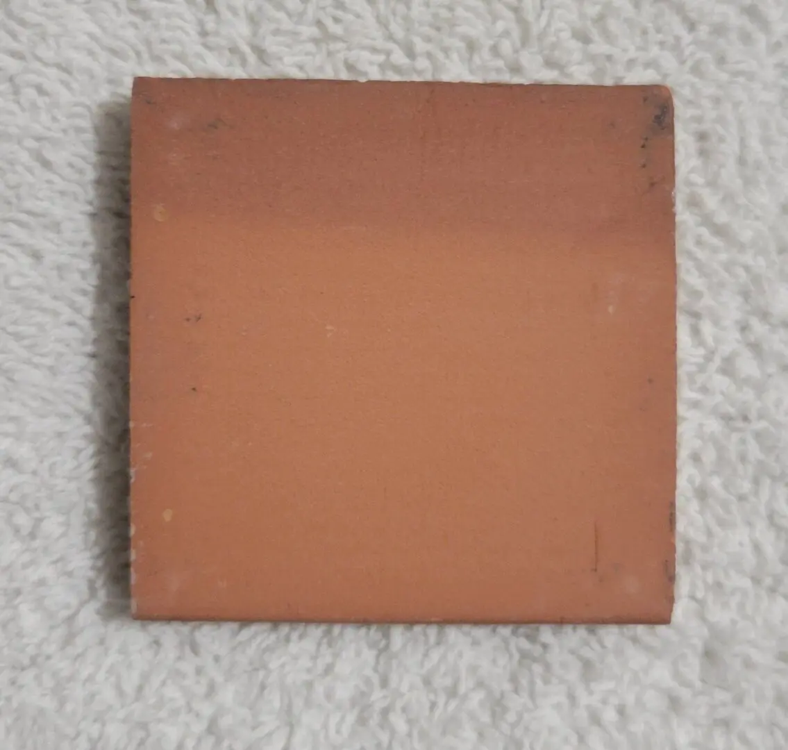 Plain square terracotta tile on white towel