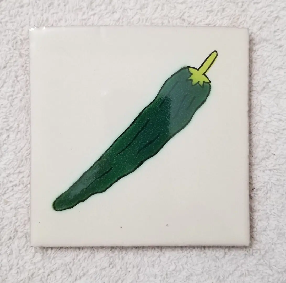 Green chili illustration on a ceramic tile.