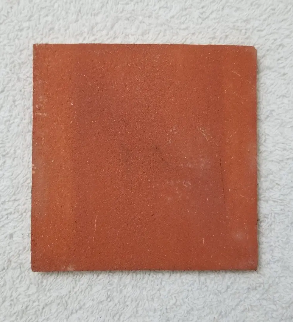 Red square ceramic tile on white surface.
