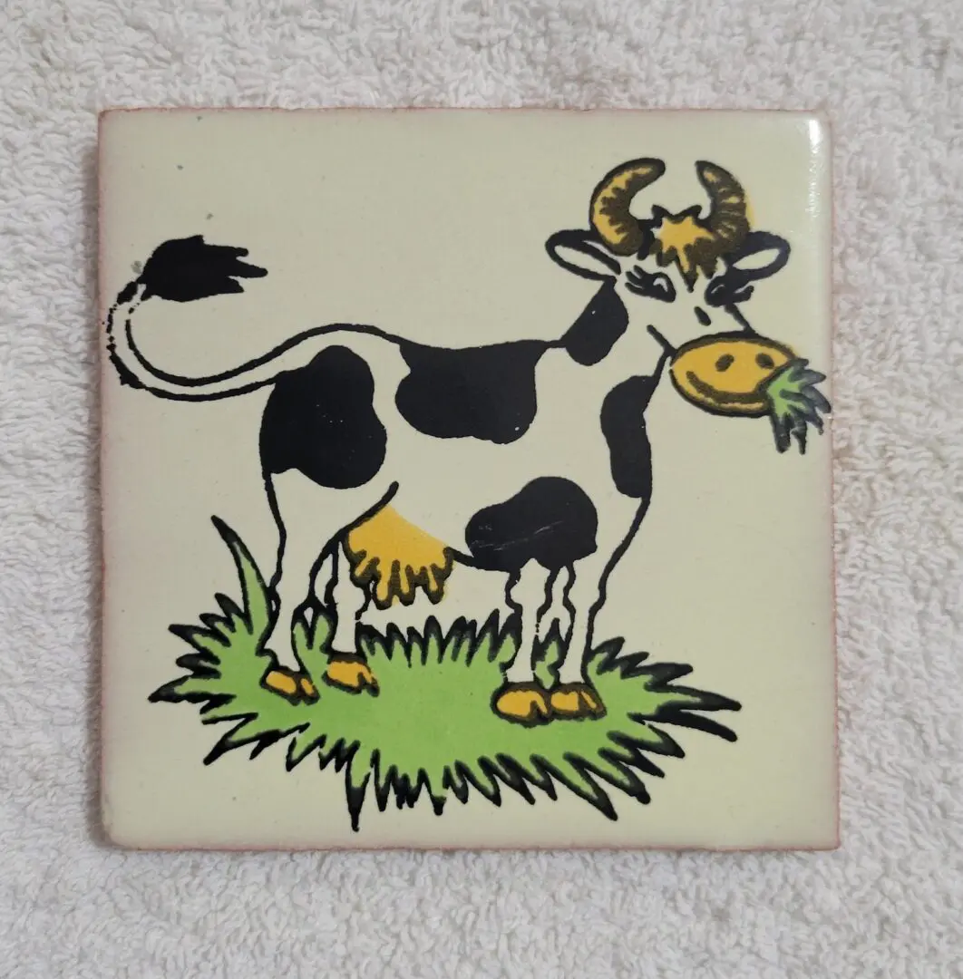 Cartoon cow eating grass on tile.