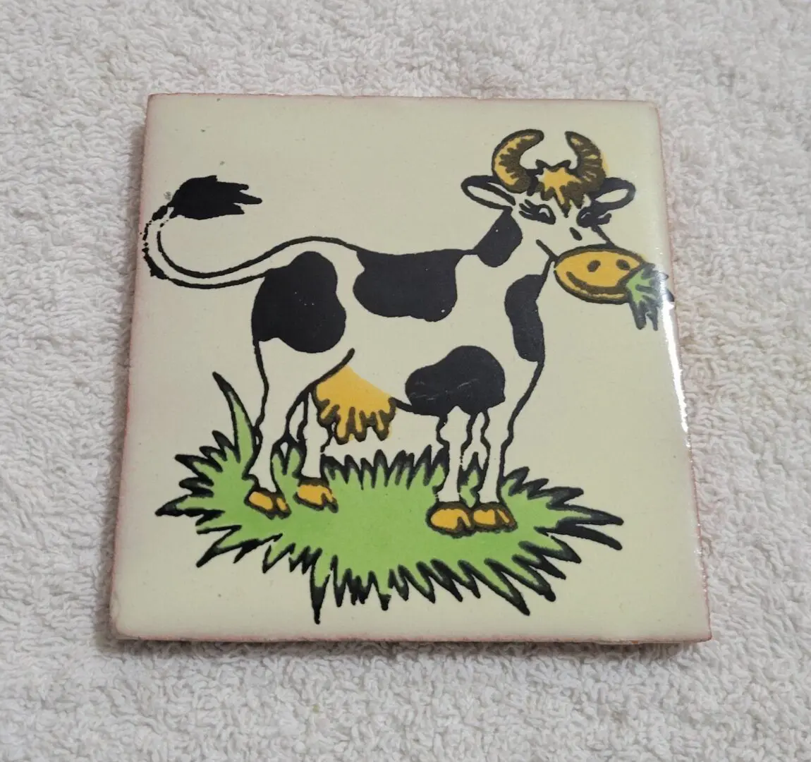 Cartoon cow on a decorative tile.