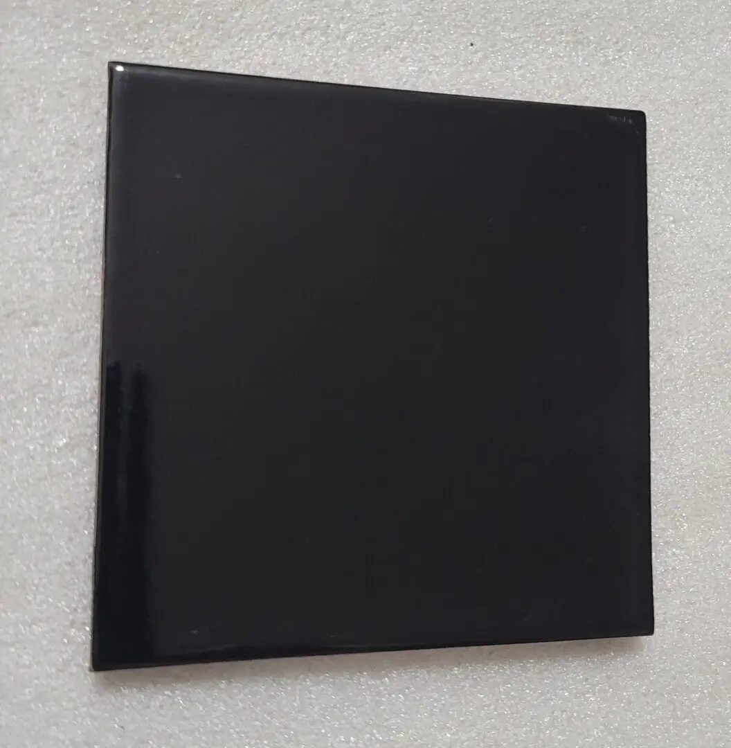Black square tile on a white surface.