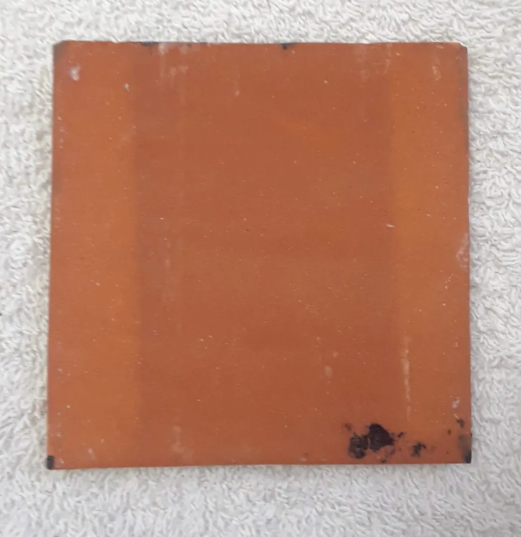 Orange square tile on textured surface.
