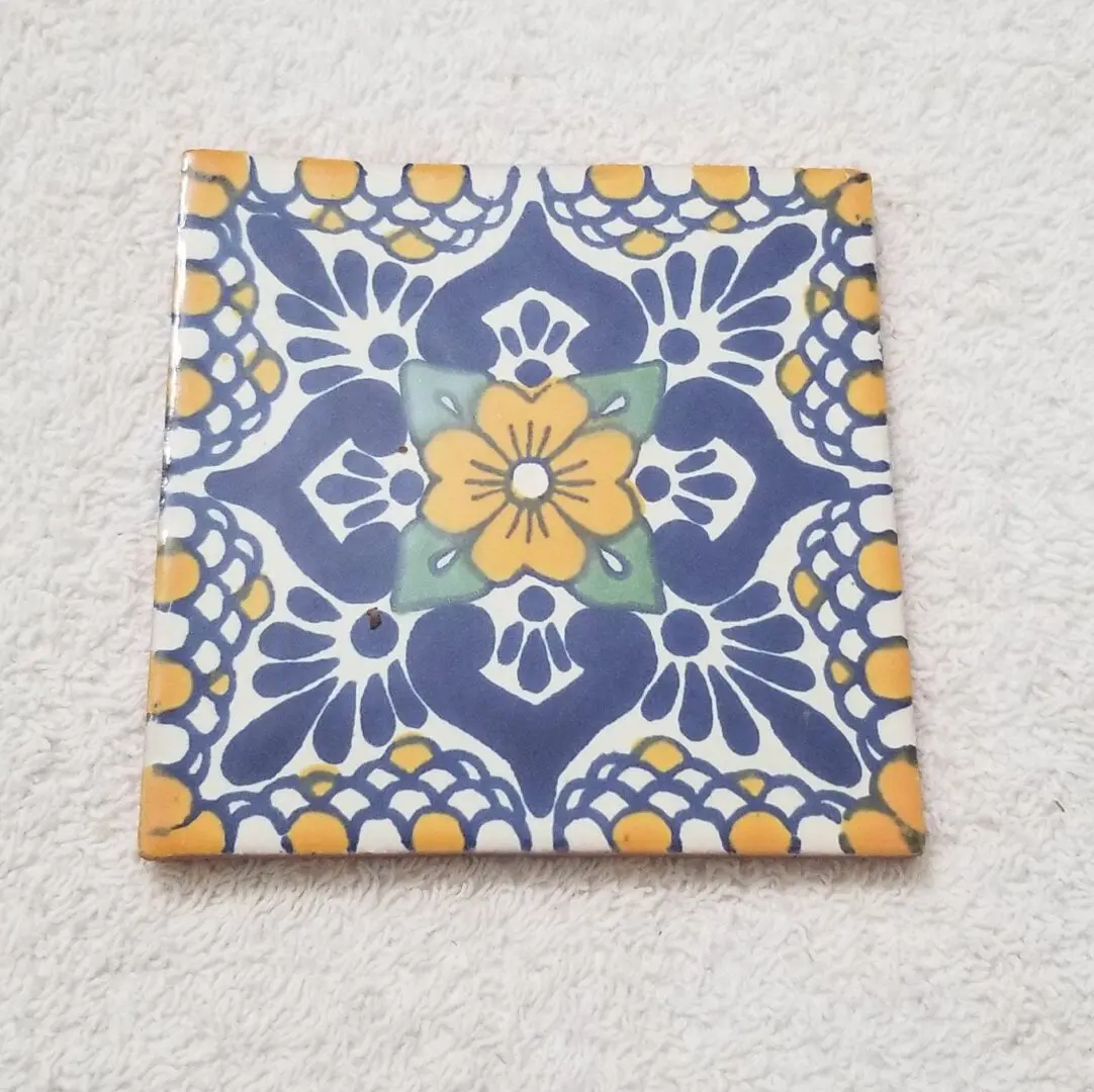 Decorative ceramic tile with blue, yellow, and white floral pattern.