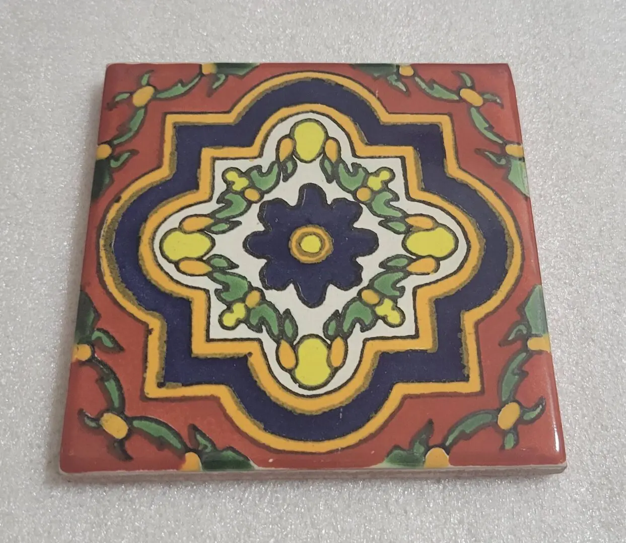 Colorful geometric ceramic tile with floral pattern.