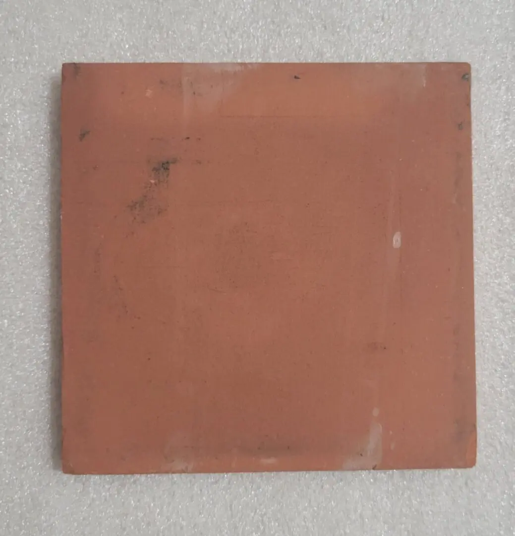 Red square tile on textured surface.