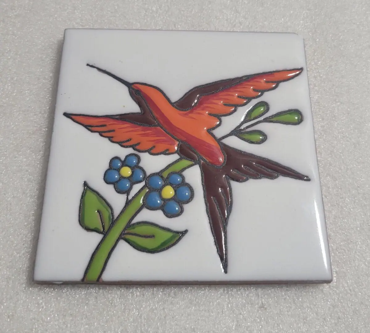 Tile with a colorful bird perched on a flower branch.