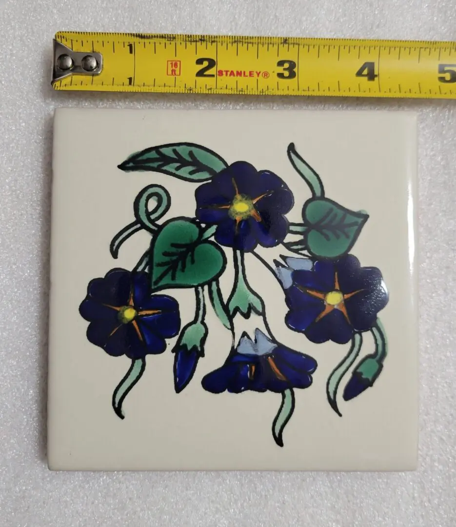 Tile with blue flower design and ruler.