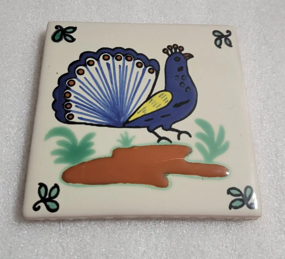Decorative ceramic tile with a peacock design.