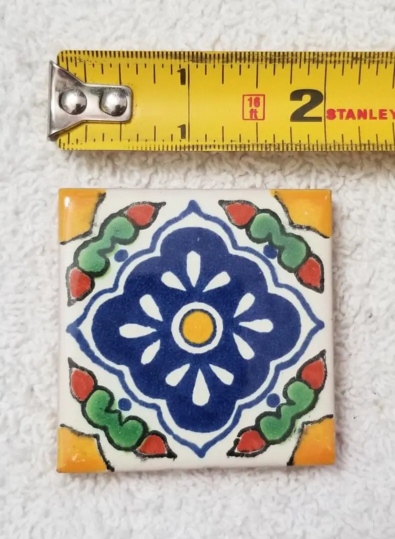 Colorful floral ceramic tile beside measuring tape