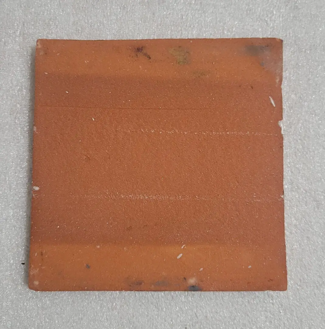 Square red-brown tile on gray background.