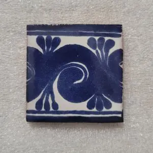 Blue and white decorative ceramic tile with floral and swirl pattern.