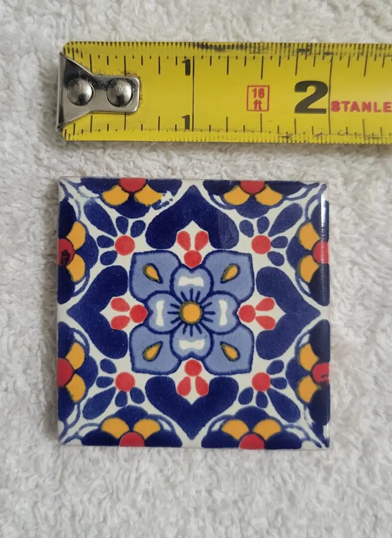Colorful decorative tile with floral pattern and ruler for scale.