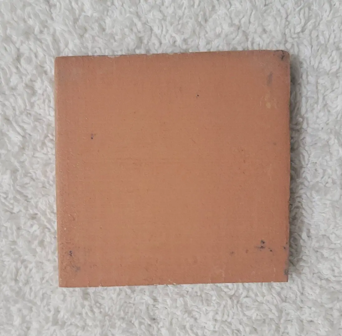 Square terracotta tile on white textured fabric