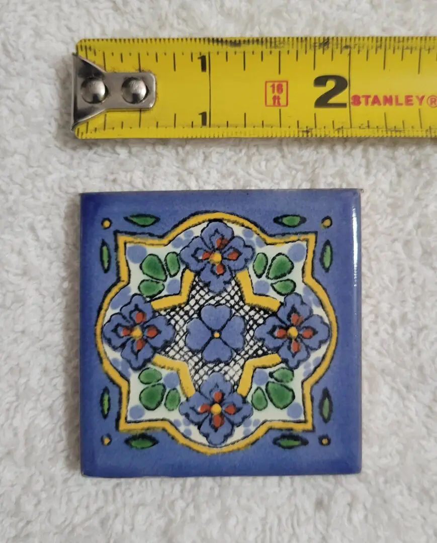 Decorative tile beside a yellow measuring tape.