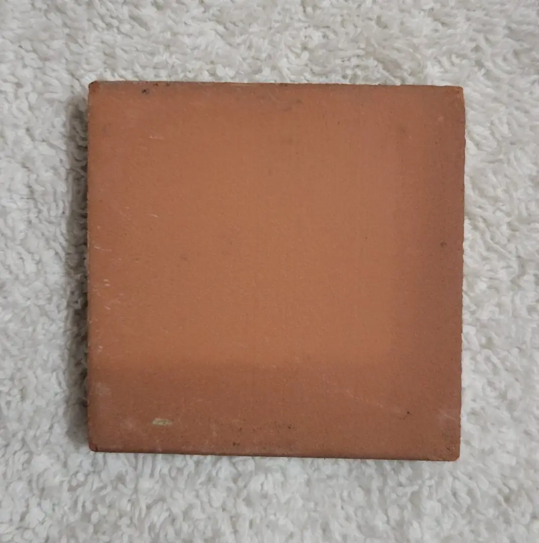 square terracotta tile on white textured fabric