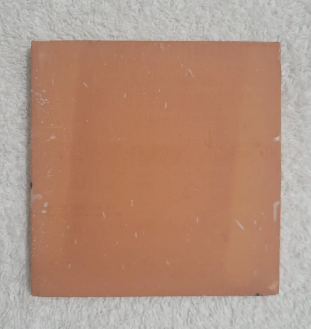 Square terracotta tile with slight surface textures and earthy tones.