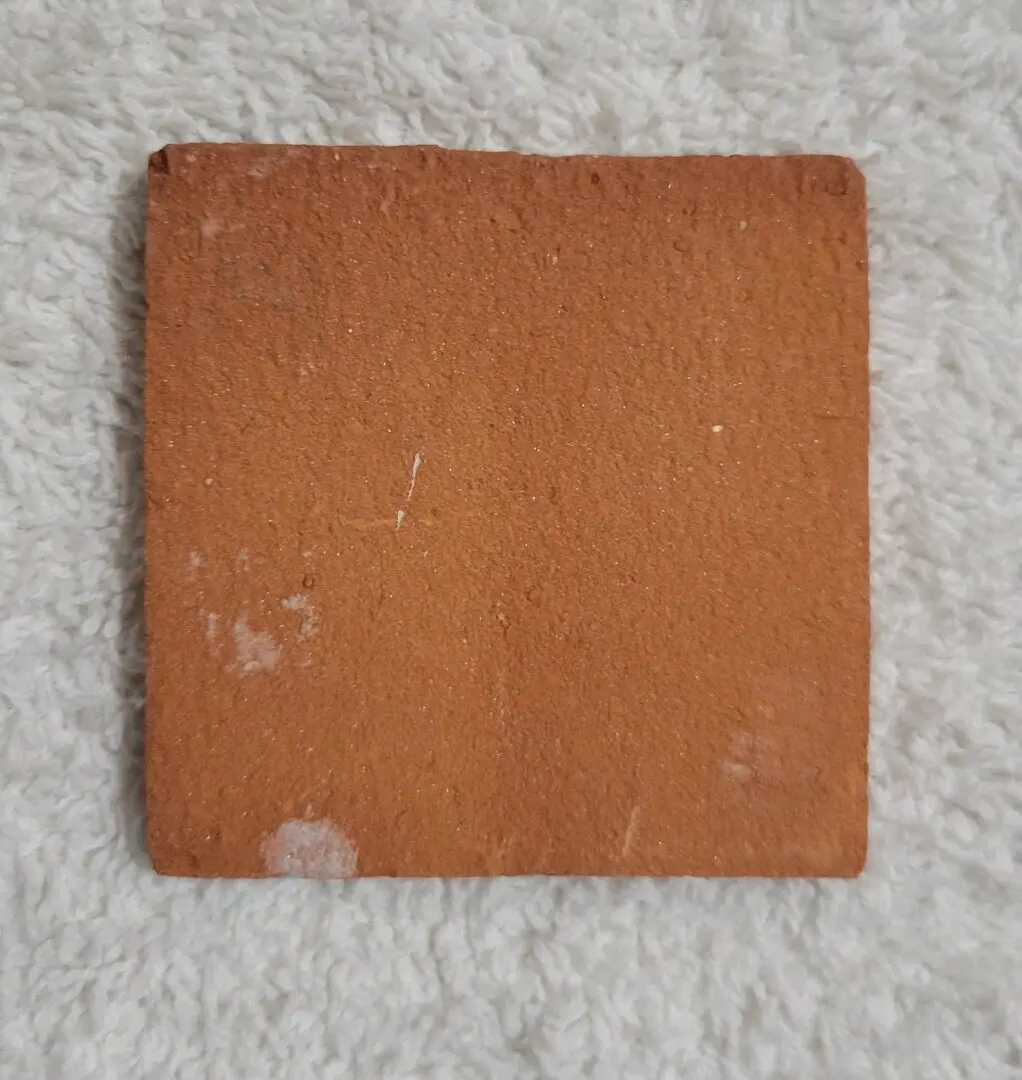 Aged square terracotta tile on white towel