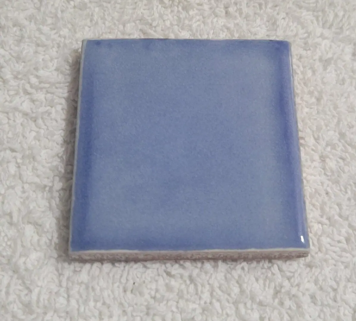 Blue ceramic tile on white textured background.