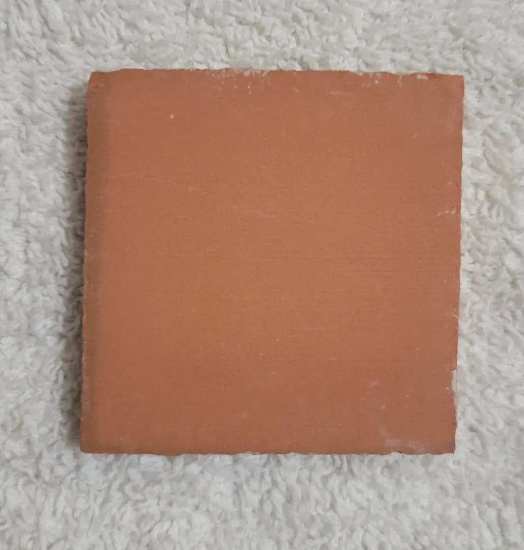 Square terracotta tile on white textured fabric