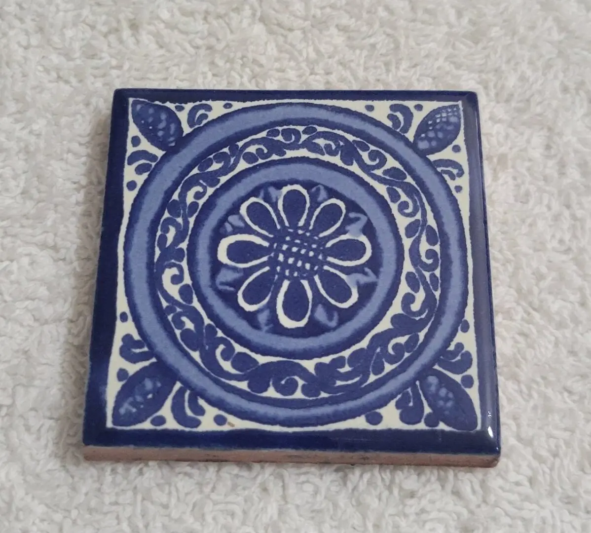 Blue floral ceramic tile on white background.