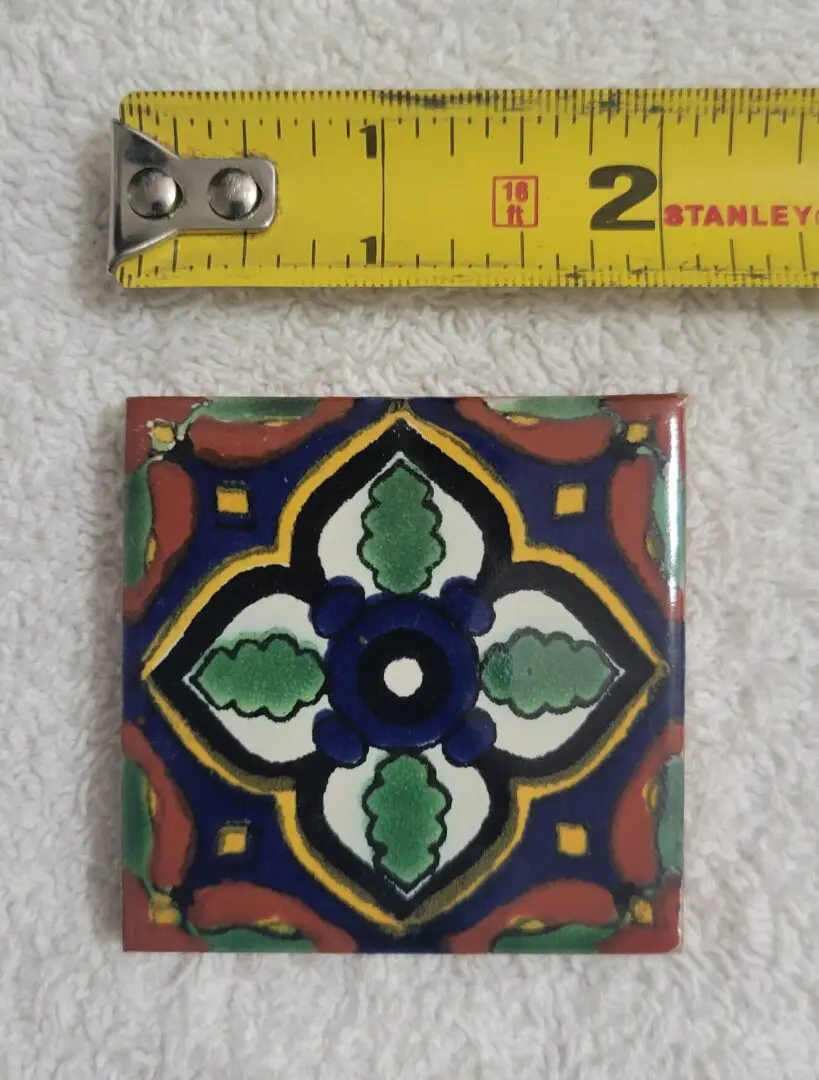 Colorful decorative tile with measuring tape above.