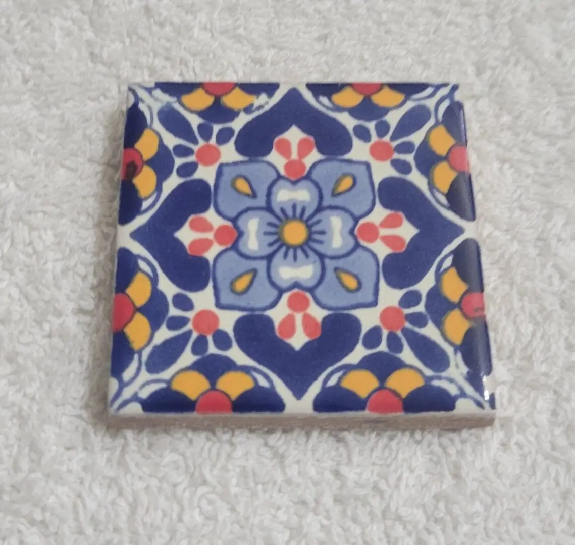 Colorful ceramic tile with a floral pattern on a textured surface.