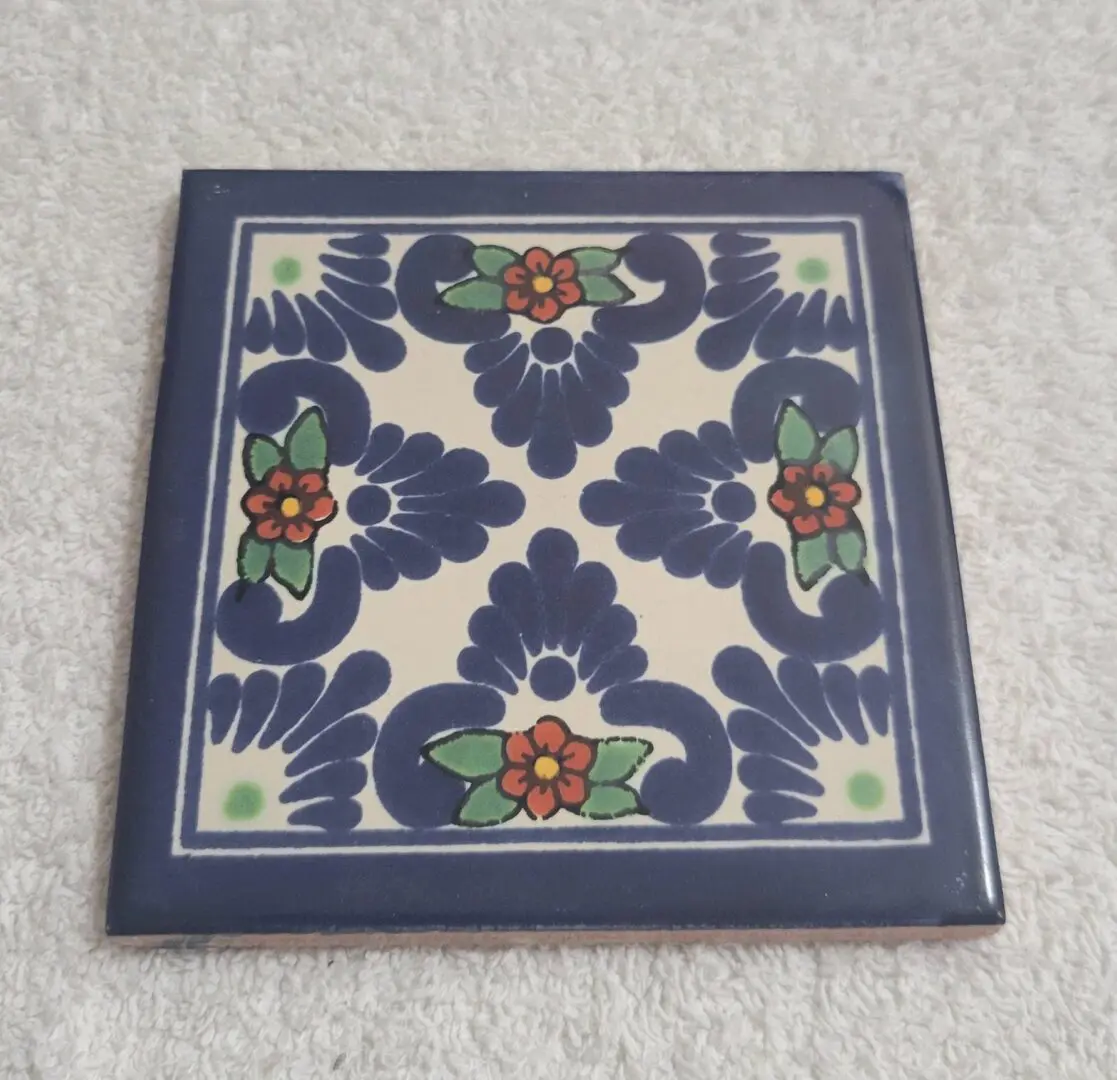 Decorative ceramic tile with floral pattern in blue, green, and red.