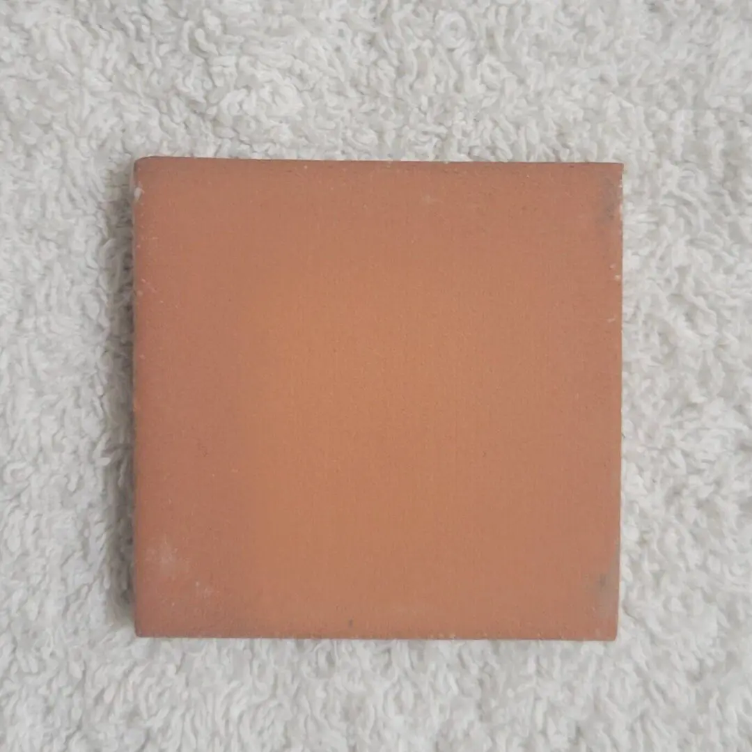 Square terracotta tile on white towel