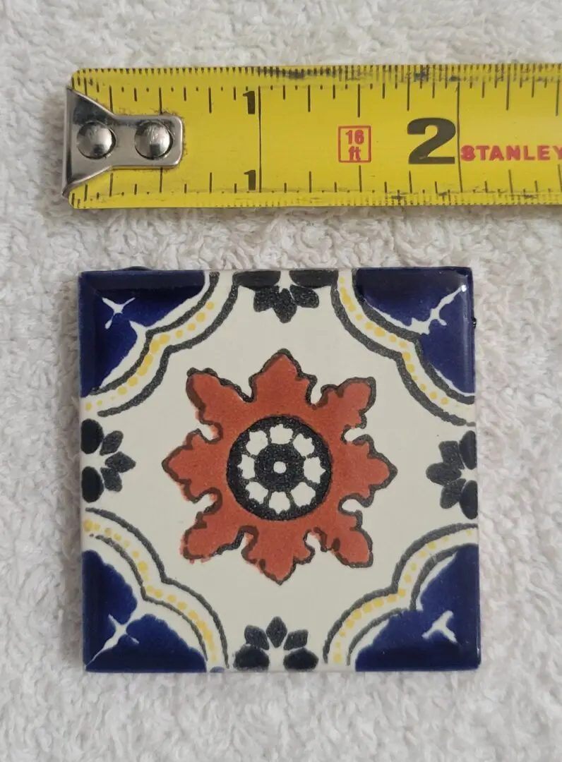 Decorative tile with tape measure beside it.