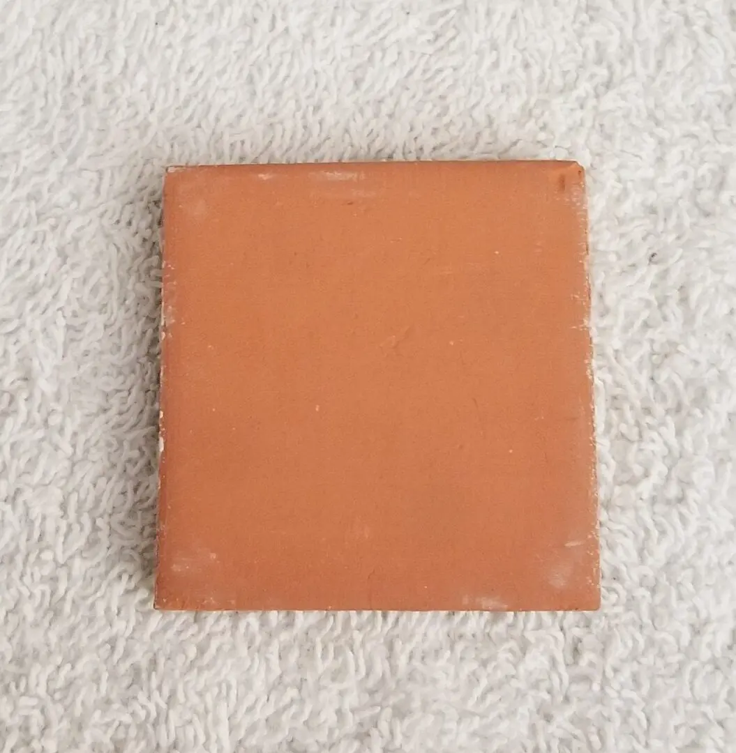 Terracotta tile on a textured surface.