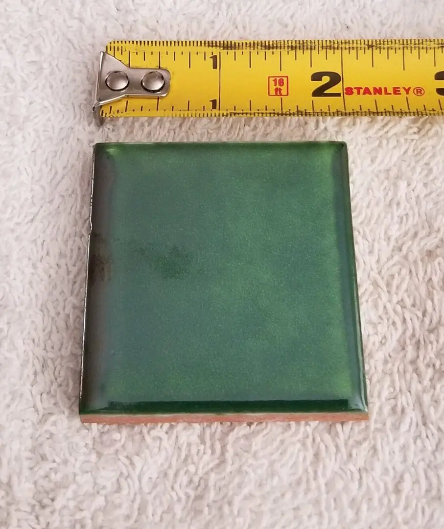Green tile with measuring tape on towel.