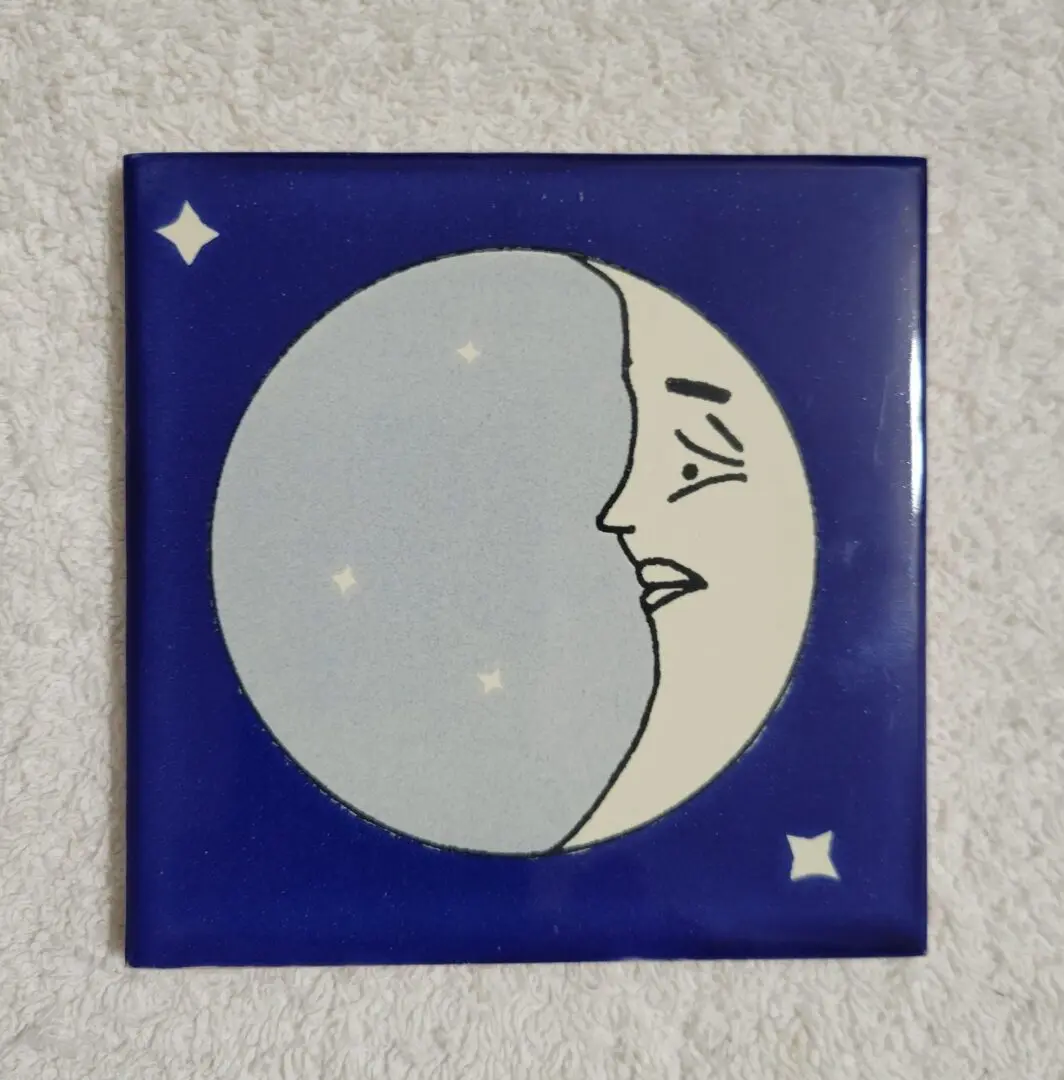 Illustrated moon face on blue background tile.