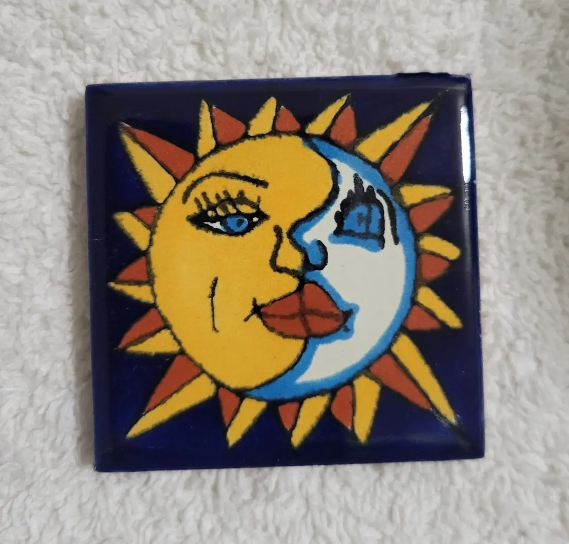 Decorative sun and moon face tile with vibrant colors.