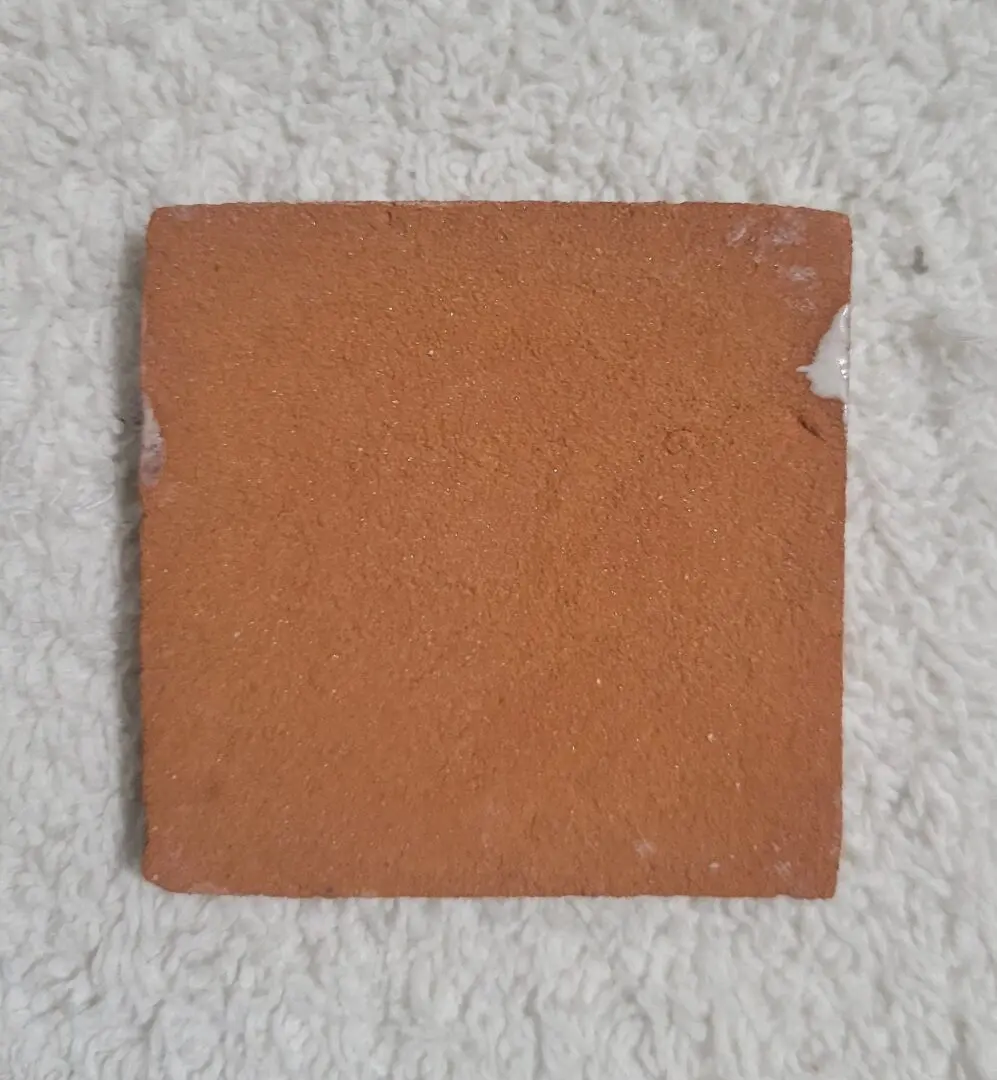 Square piece of brown bread with a bite taken out on a white textured surface.