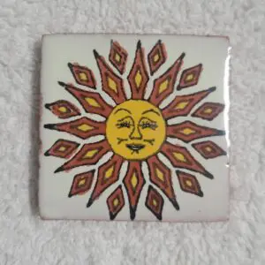Decorative tile featuring a stylized sun with a face and radiant rays.