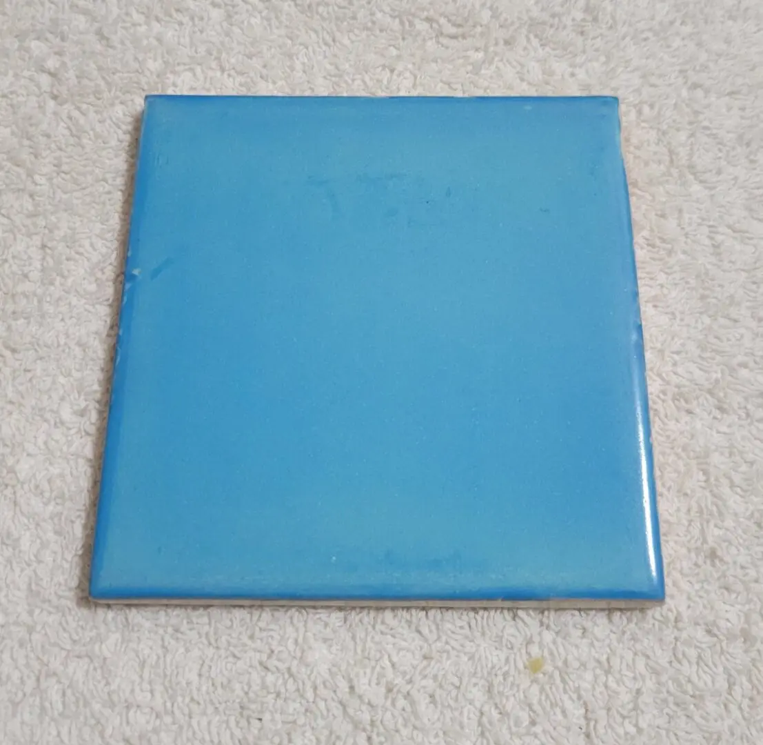 Blue ceramic tile on textured surface.