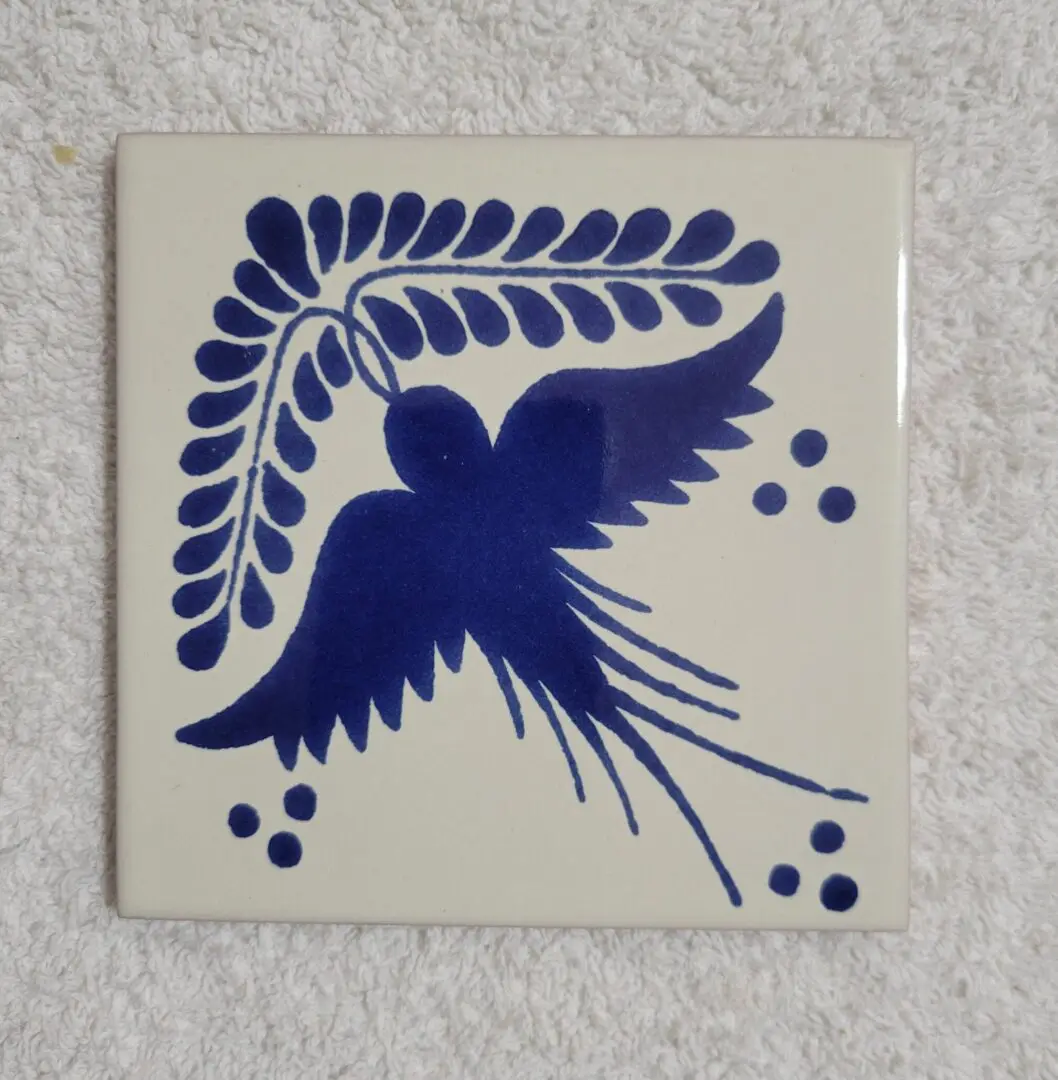 Decorative tile with a blue bird and leaf design.