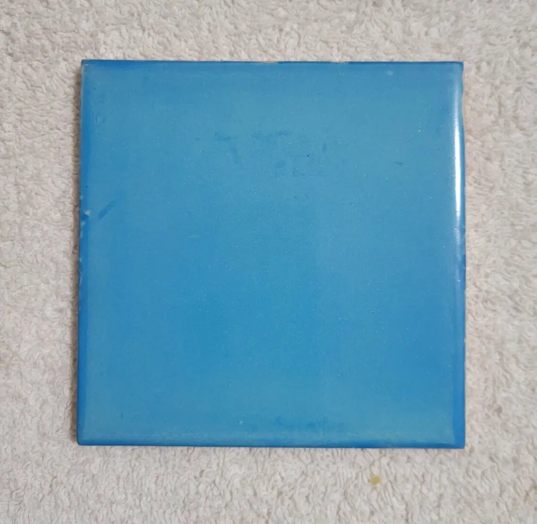 Blue square tile on textured surface.