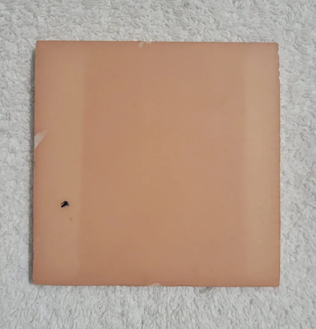 Square tile on textured white background.