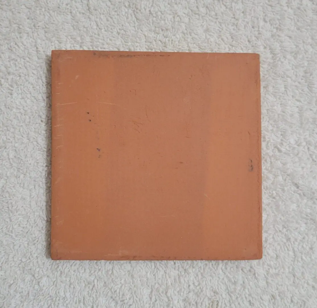 square terracotta tile on white textured towel