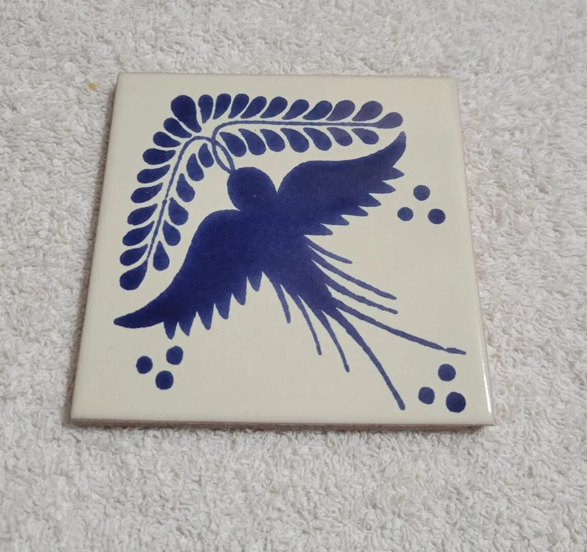 Blue bird design on a white ceramic tile.