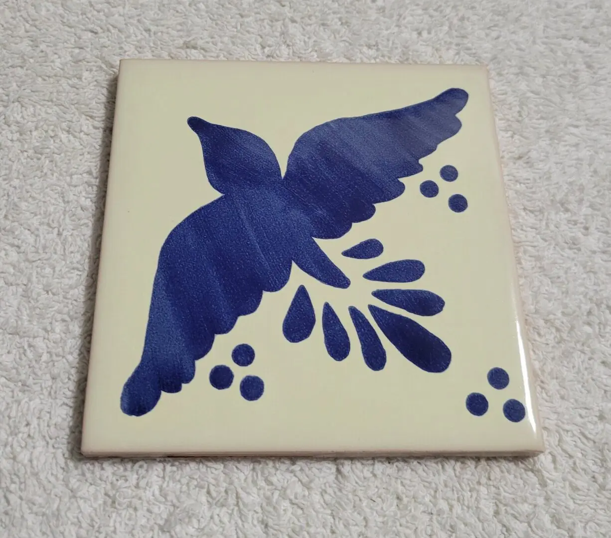 Blue bird ceramic tile with berry motif