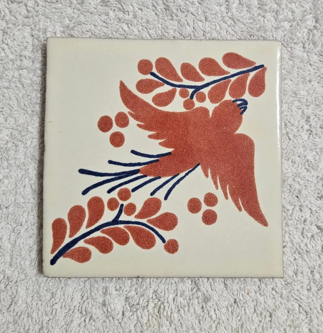 Decorative tile with bird and leaf design.