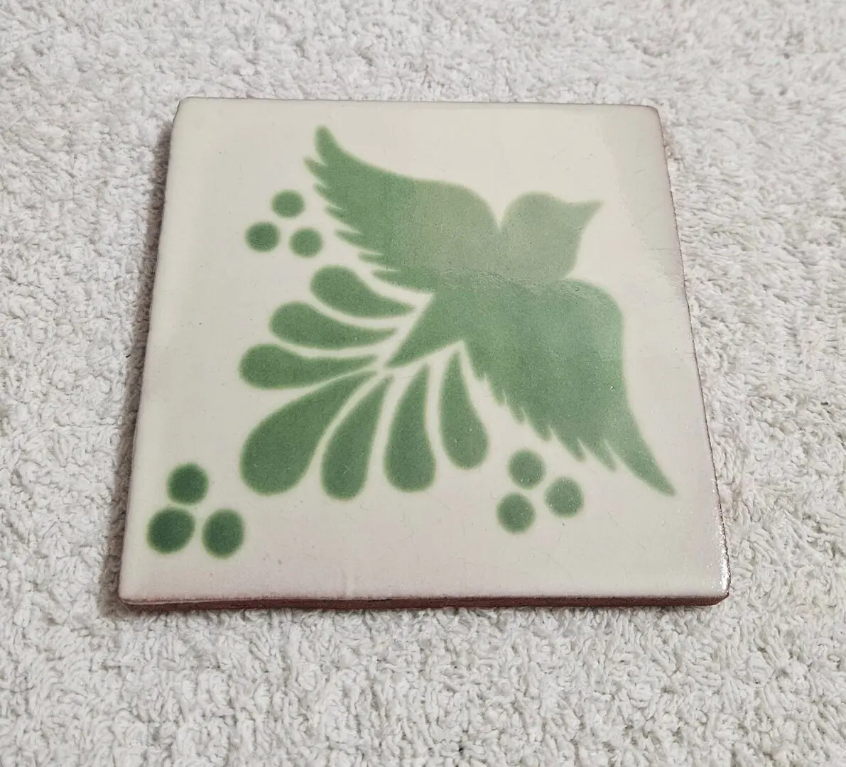 Green stylized bird on ceramic tile