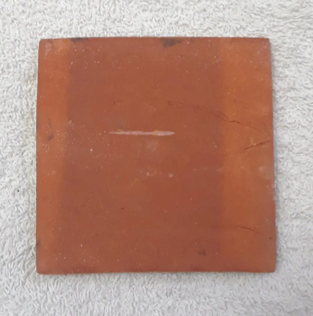 Red clay square on textured surface.