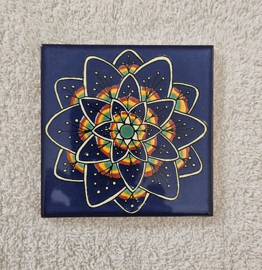 Colorful geometric mandala on blue square tile.