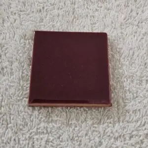 A closed, maroon-colored book on a textured surface.